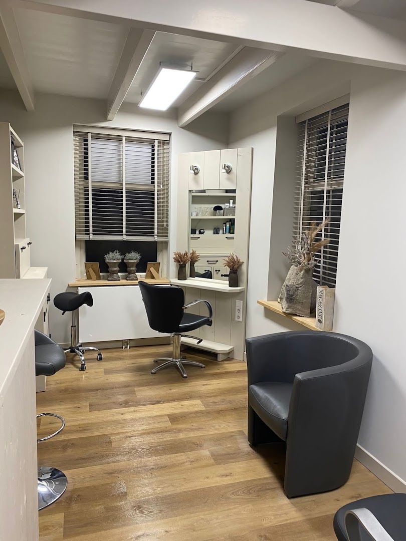 De salonruimte van Claudia's Hairstyling in Almkerk, met kappersstoel, spiegelmeubel en warme leren fauteuil